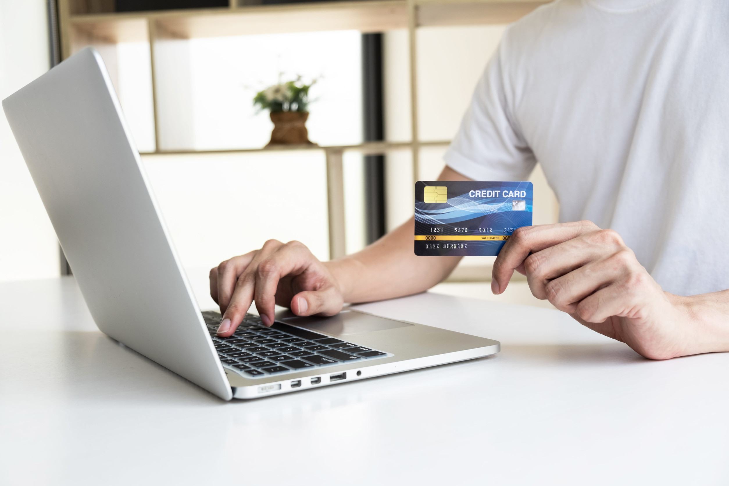 A Man Using A Laptop And Holding A Credit Card