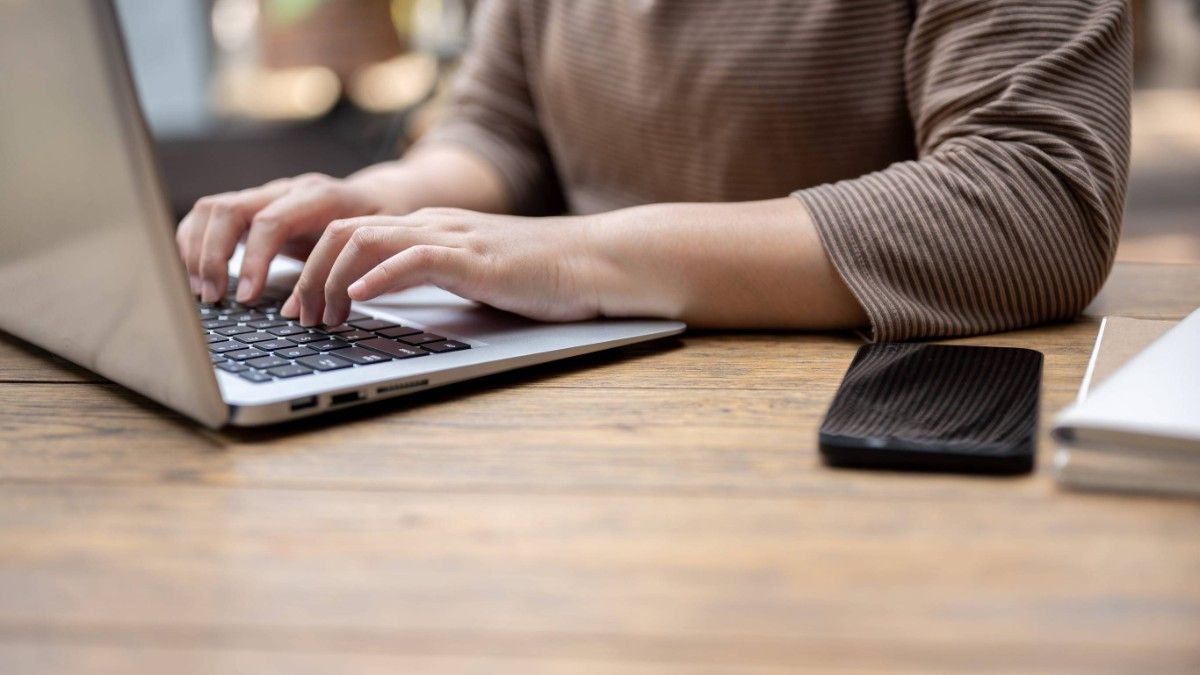 A Person Typing On A Laptop