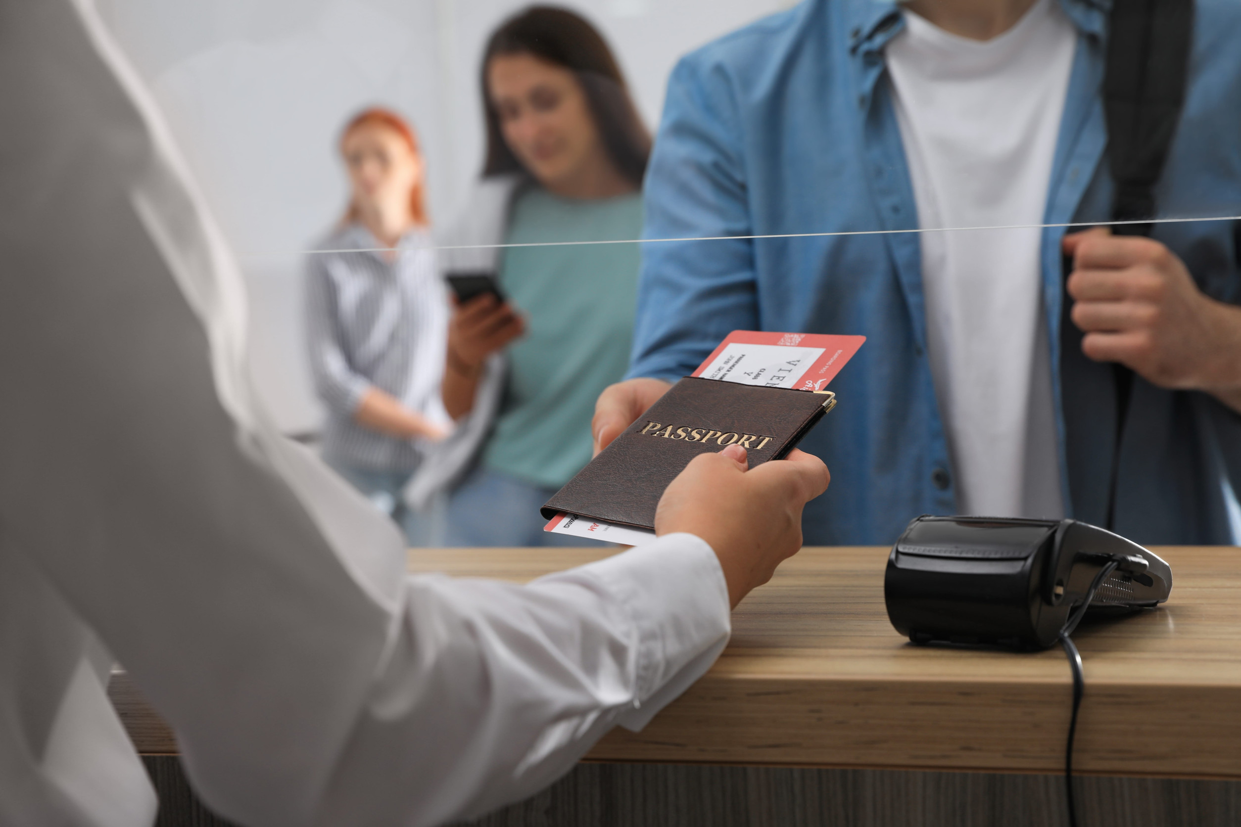 Agent Giving Passport With Ticket To Client At Check-In Desk In Airport