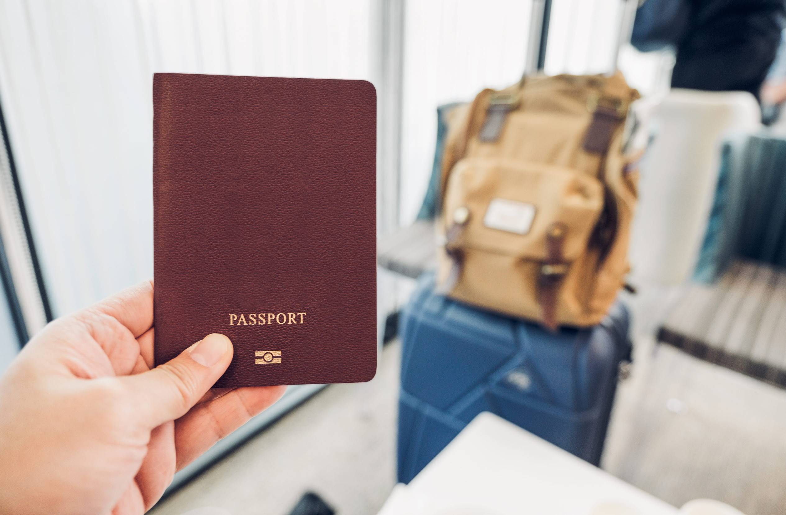Hand Holding a Passport at Airport Terminal