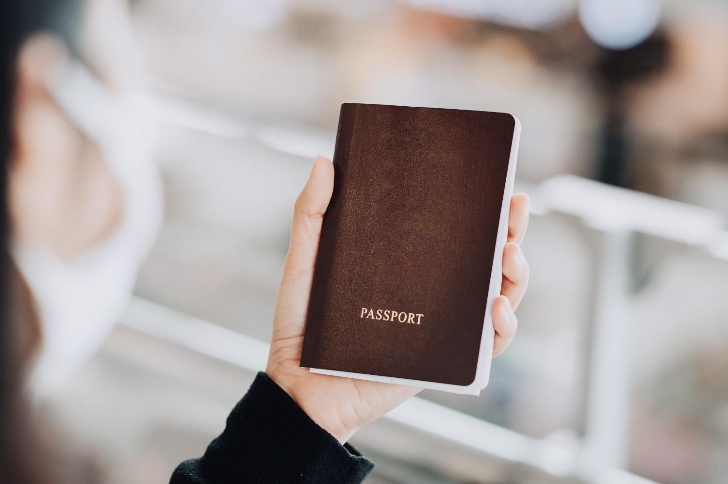 Masked Woman Traveler Sitting with Passport Using Smartphone