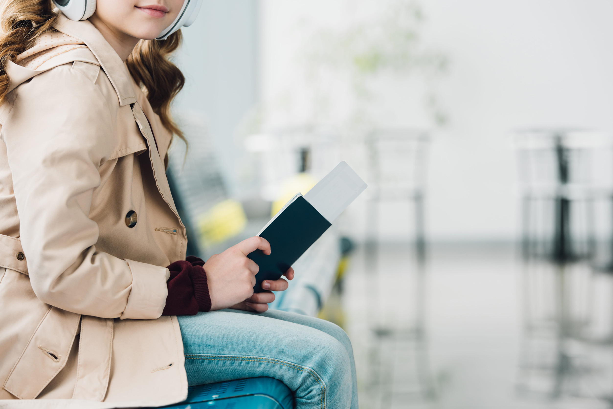 Preteen Kid with Passport Listening to Music in Airport Waiting Hall