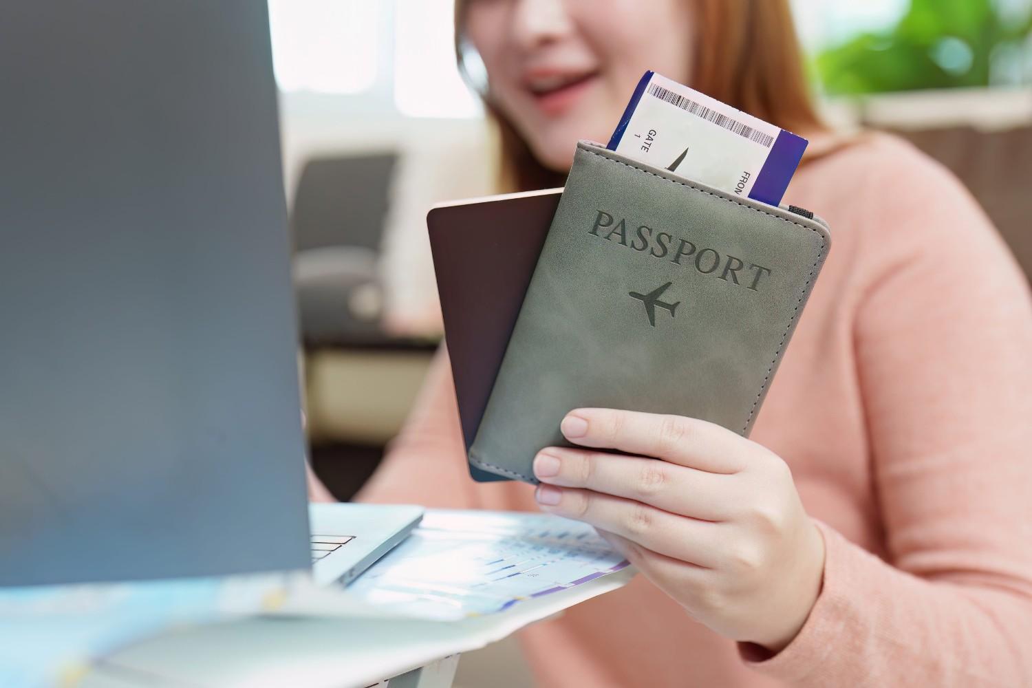 Woman Holding Passport And Flight Ticket Using Laptop