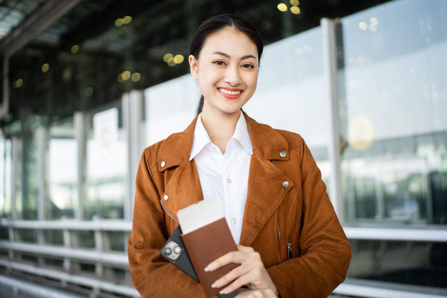 Woman Holding Passport with Ticket, Boarding Pass, and Smartphone